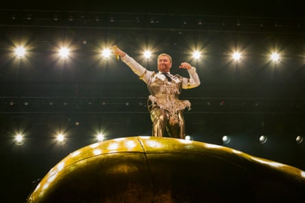 Wearing a gold outfit over a white shirt, they ride the object as though surfing
