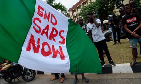 A demonstrator with the Nigerian national flag where someone has written "Ends SARS Now"