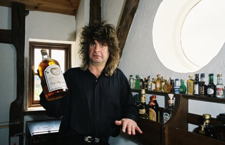 Black Sabbath singer Ozzy Osbourne holding a large bottle of whiskey at his home in 1988