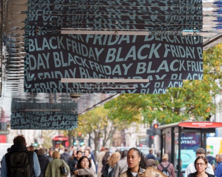 Banners advertising reductions for the next Black Friday hang above the heads of shoppers passing the John Lewis department store on Oxford Street in London