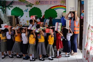 Small children with books on heads and teacher