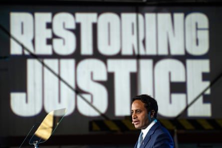 Zia Yusuf in front of a giant sign that says 'restoring justice'