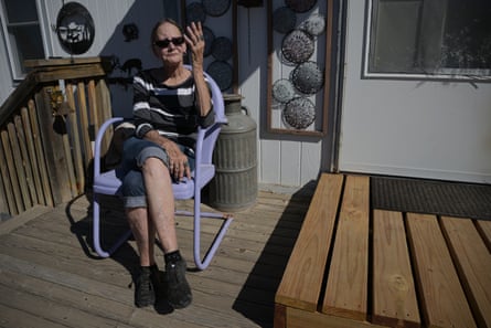 A woman sits on a chair on patio.