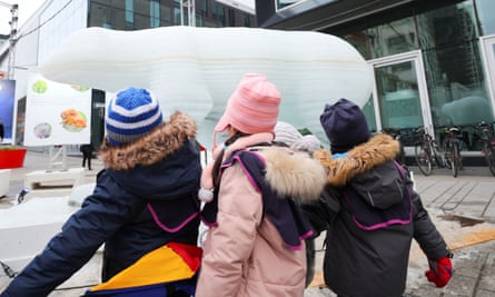 Children looking at an ice sculpture of a polar bear.