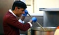 Rishi Sunak, wearing blue disposable gloves, stirs a large cooking pot in a kitchen