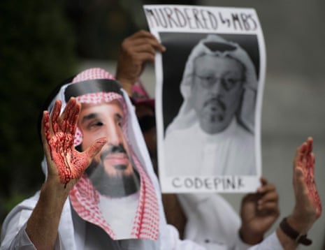 In this file photo taken on October 10, 2018, a demonstrator dressed as Saudi Arabian Crown Prince Mohammed bin Salman with blood on his hands protests outside the Saudi Embassy in Washington, DC, demanding justice for the death of Saudi journalist Jamal Khashoggi, in the picture being held by another protester.