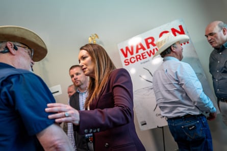 A middle-aged woman speaks with men in cowboy hats.