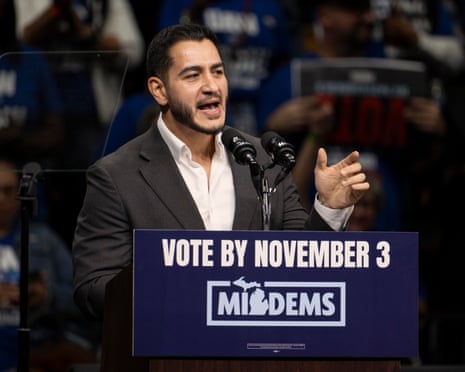 Abdul El-Sayed, a man in a grey suit jacket, speaks into microphone at lectern marked 'Vote by November 3' with a hand gestured