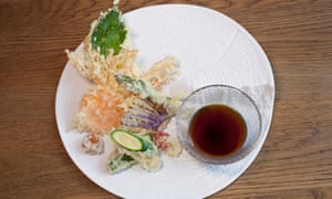 A round which plate with vegetable tempura and a small bowl of dip
