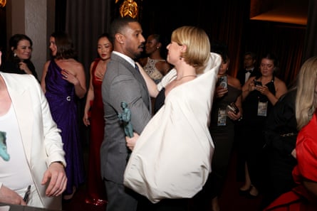 woman in white dress and man in grey suit talk