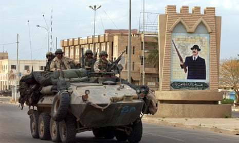 Marines in a light armoured vehicle pass a Saddam Hussein portrait in the centre of Tikrit in 2003.