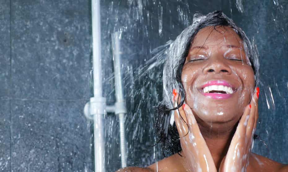 domestic lifestyle portrait of young happy and beautiful black afro American woman smiling happy taking a shower at home bathroom washing her hair with shampoo in beauty and hygiene concept