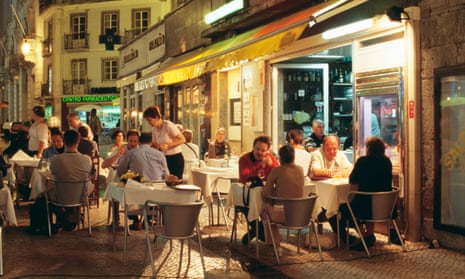People sit at restaurant tables in the Baixa district of Lisbon