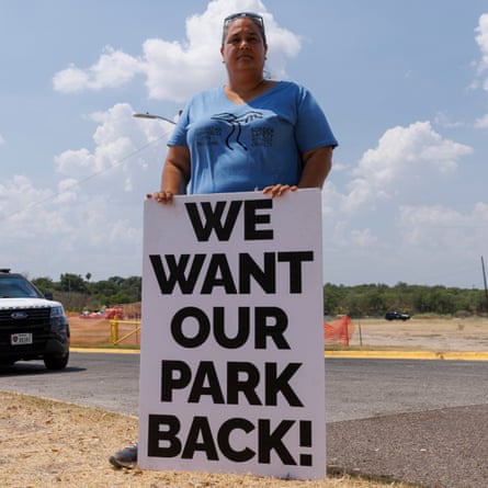 A woman poses outdoors with a sign saying “We want our park back!”