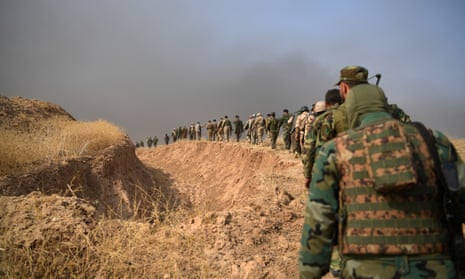Kurdish peshmerga soldiers walk alongside a trench near Mosul, Iraq