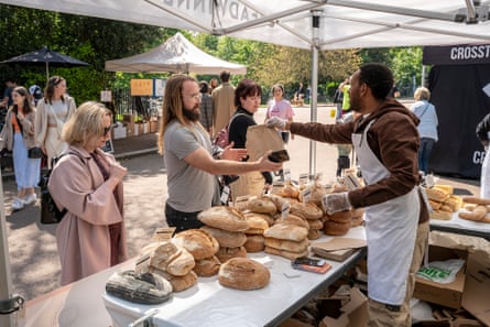 في سوق فيكتوريا بارك، يبيع عبديسا، وهو لاجئ من إثيوبيا، مدير كشك، الخبز لعميل محلي.