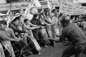 Buddhist monks and women pull at a barbed-wire road barricade that was set up in front of Saigon’s Giac Minh Pagoda to halt a demonstration, July 17, 1963