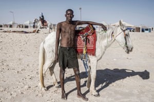 Nouakchott, Mauritania. A man poses next to a horse at a popular beach in the Tefargh Zeina district