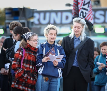 Three protesters read the constitution in front of a banner condemning Nazis