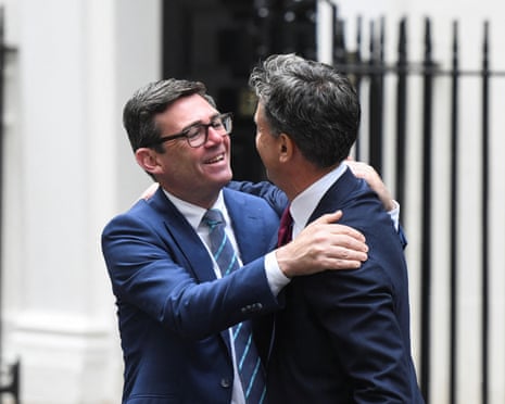 Burnham and Miliband embrace and smile at each other