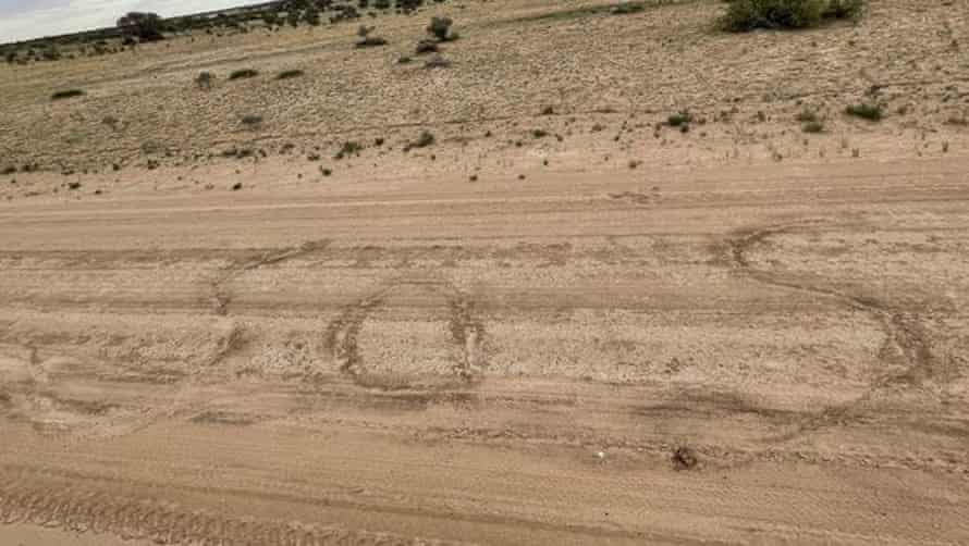 SOS scrawled on sandy road