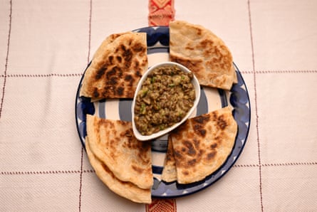 Topview of a dish of green lentils on a plate with esh, a flaky flatbread.