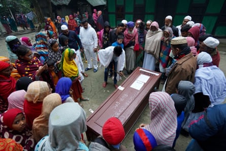 A crowd of mourners standing around a coffin