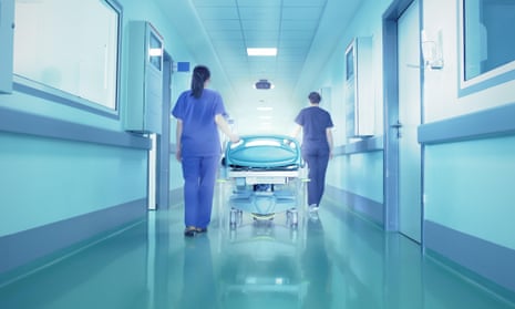 Doctor and nurse wheeling trolley down hospital corridor