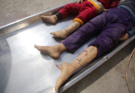 The bodies, seen from the waist down, of children from the Nateel family, with their names Hani (L) and Layan seen written on their legs where a trouser leg has been rolled up