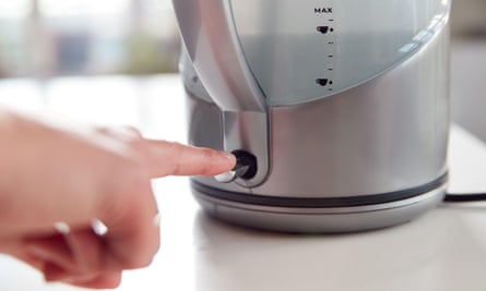 Woman pressing power switch on electric kettle