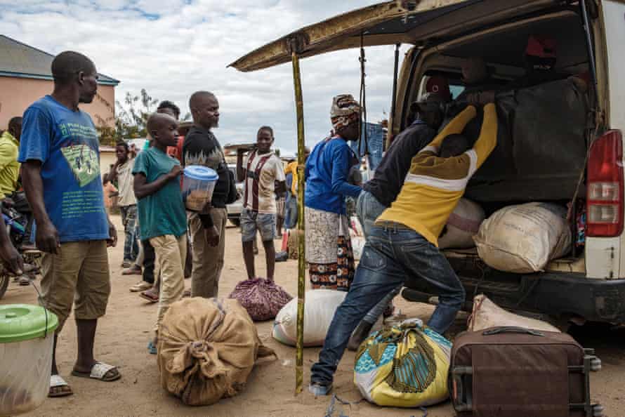 Men pack displaced people’s luggage into a minibus at the bus station