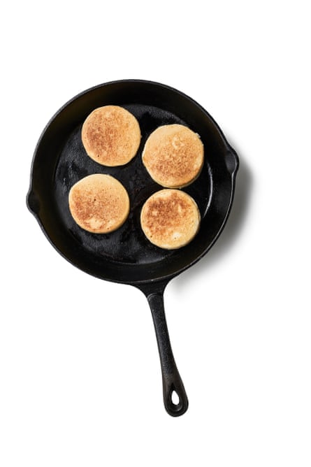 A cast iron pan with four crumpets.