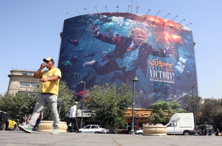A man walks past a billboard which shows Trump underwater reaching for a dollar bill that is hooked on the end of a fishing line