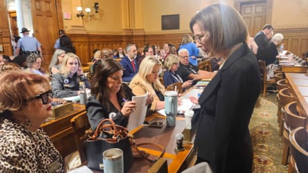 Woman standing in suit speaks with women sitting in rows.