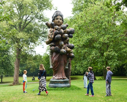 People standing near a large sculpture of a woman holding a bunch of severed heads