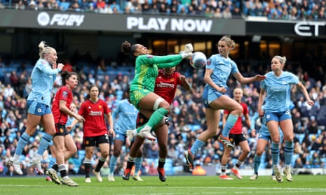 Manchester City keeper Khiara Keating punches the ball clear whilst under pressure from Geyse of Manchester United.