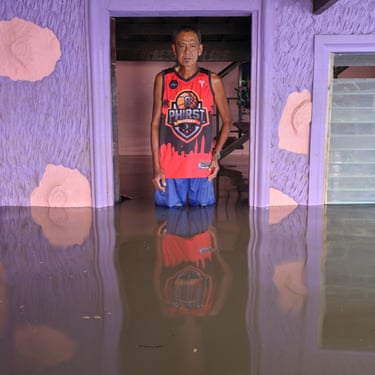 A man stands in a doorway thigh-deep in flood water