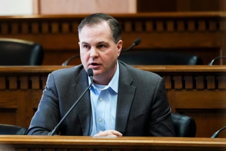 a man speaks into a microphone while seated
