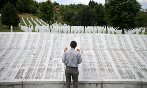 A genocide survivor prays near the graves of his father and two brothers at the memorial centre near Srebrenica