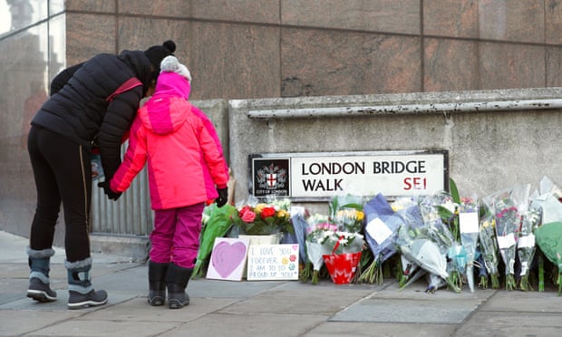 Passersby stop to look at flowers left at London Bridge in central London following the murder of Jack Merritt and Saskia Jones by Usman Khan.