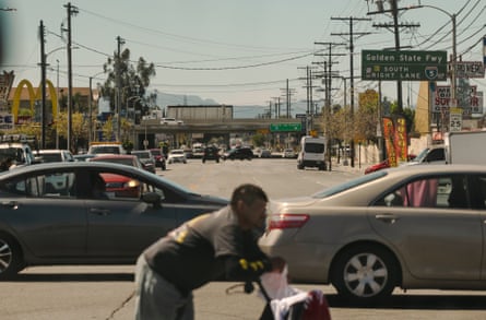 An image of a road with two cars and a boy on a cycle.