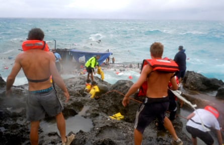 People clamber on the rocky shore of Christmas Island during a rescue attempt as a wooden boat packed with asylum seekers boat breaks up in 2010.