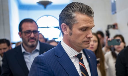A man with large sideburns in a suit looks downward.