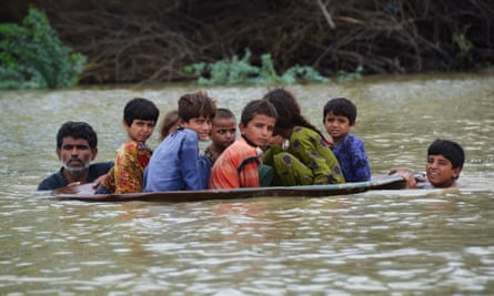 Children are moved across a flooded area in a satellite dish