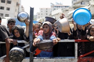 Palestinians wait to receive food from a charity kitchen in Gaza City