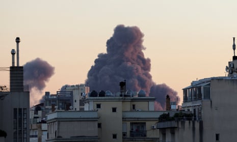 Smoke rises behind city buildings