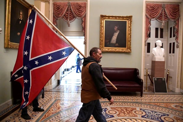 A member of a pro-Trump mob carries a Confederate battle flag on the second floor of the US Capitol.