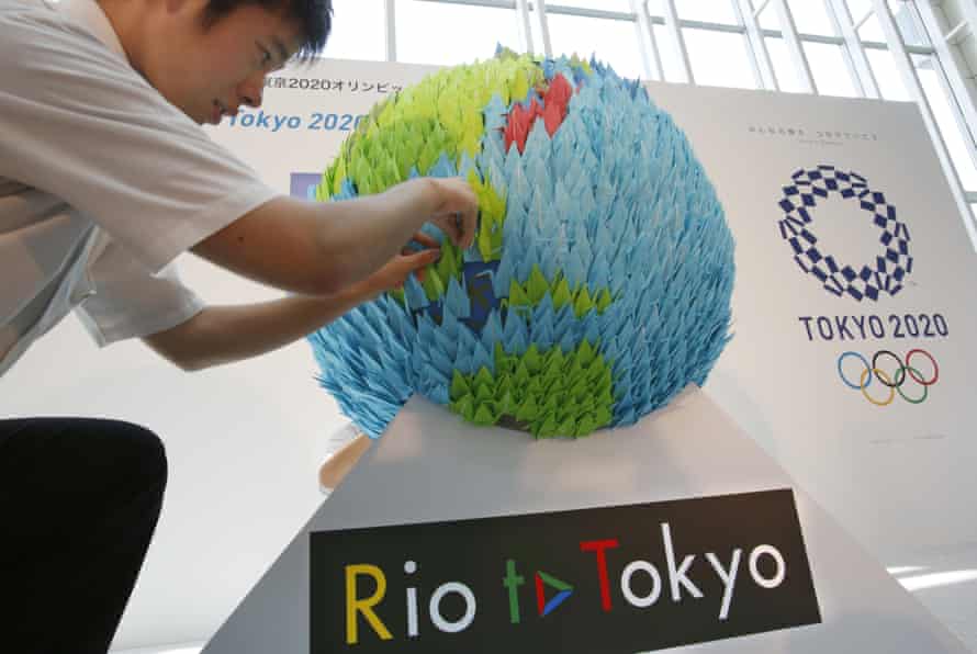 A man adjusts a display for a 2020 Tokyo Olympic countdown event at Haneda airport in Tokyo, Sunday, July 24, 2016. The giant globe is made from 2,020 origami paper cranes. (AP Photo/Shizuo Kambayashi)