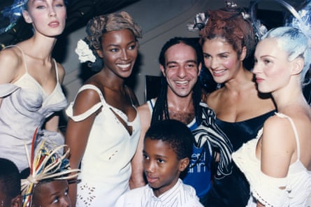 A man in cornrows poses with supermodels
