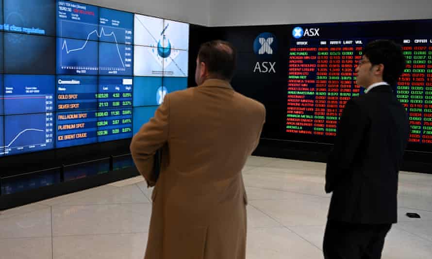 People watching ASX graphs on monitors